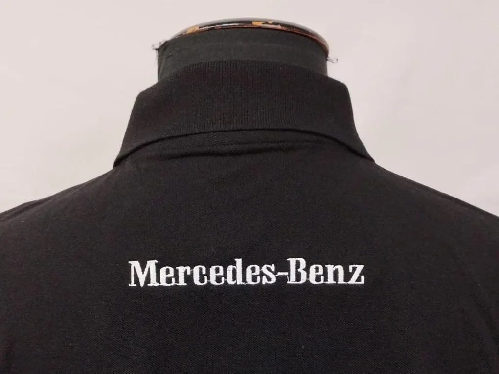 Marca bordada en la nuca de un polo negro, bajo el cuello
