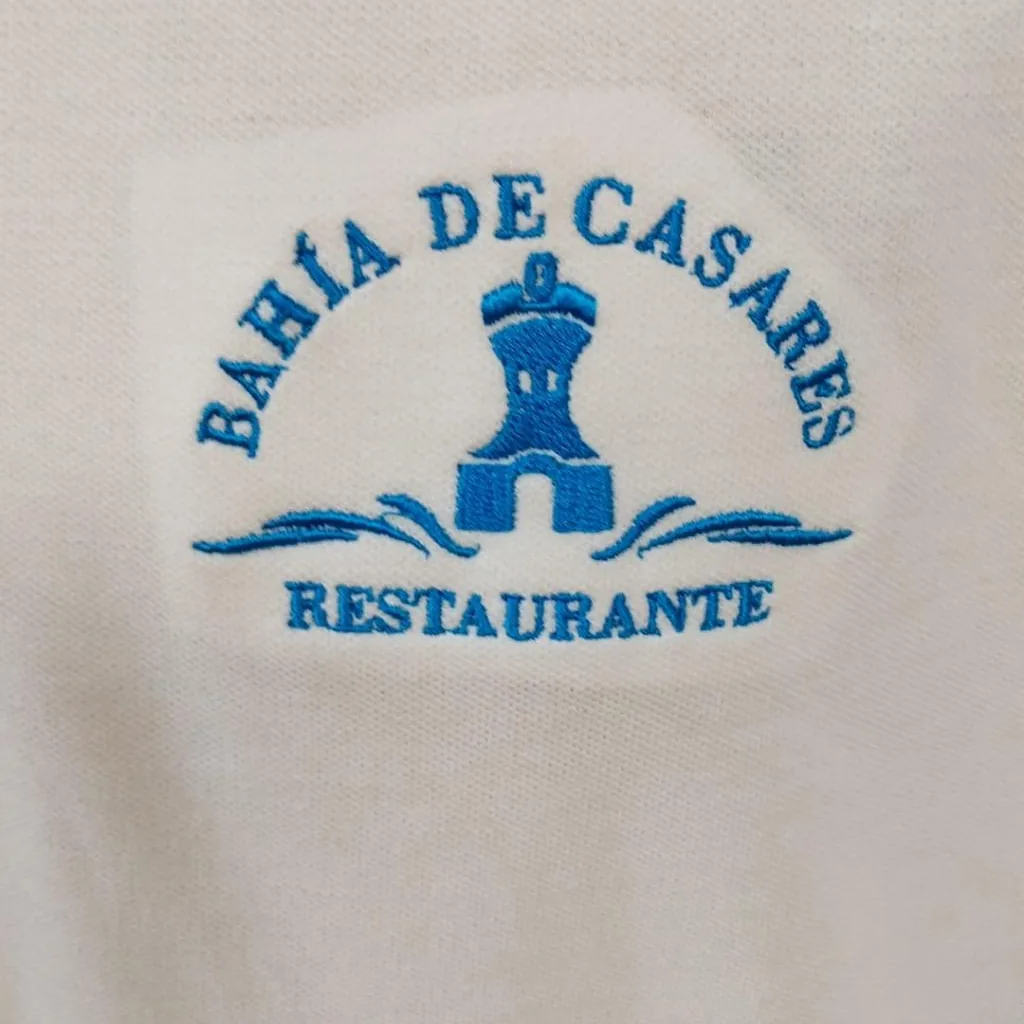 Polo blanco con bordado de escudo azul en el pecho