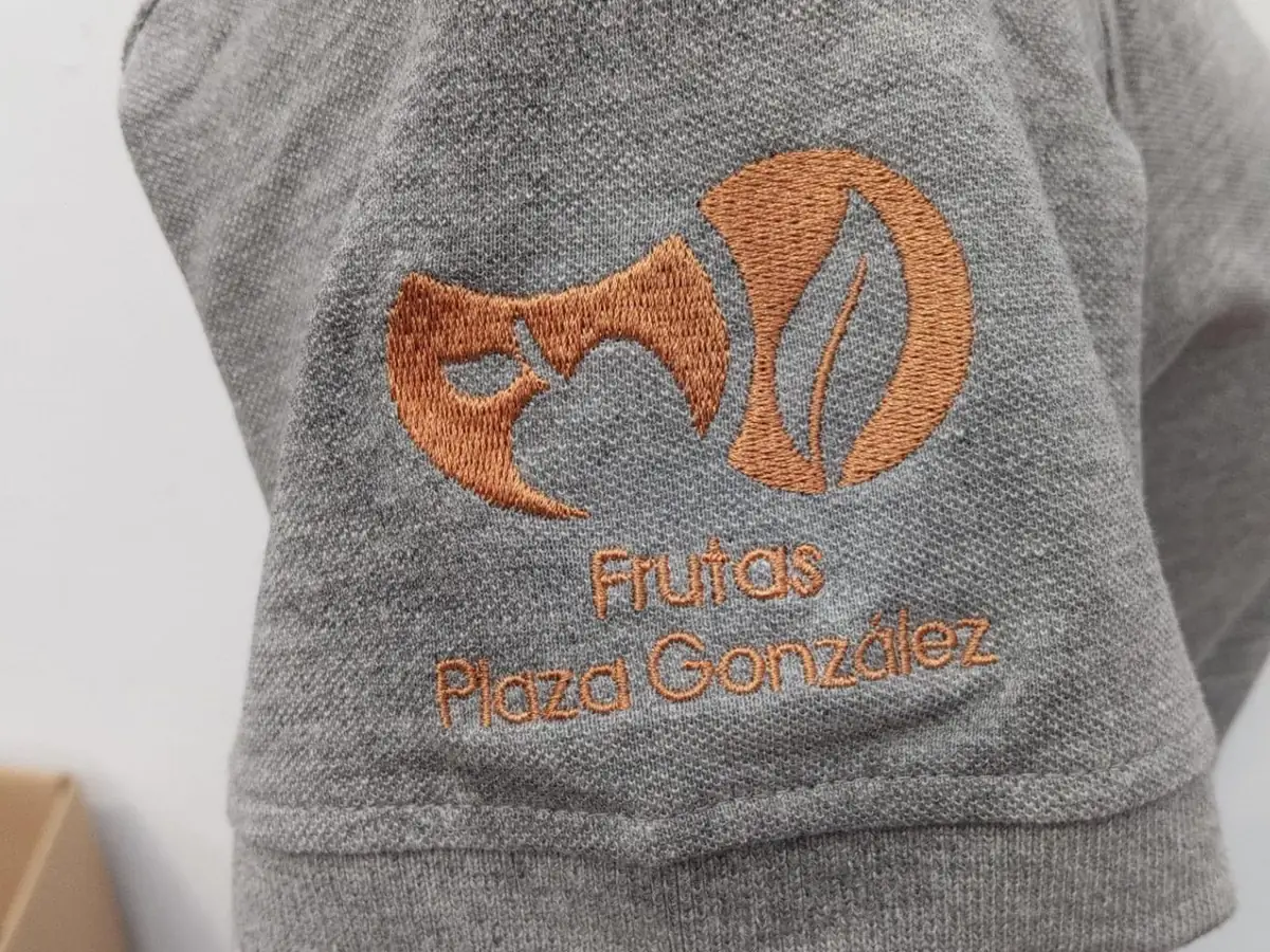 Logotipo bordado en la manga de un polo gris
